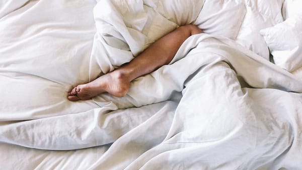 Bed showing somebody sleeping in it with only leg visible