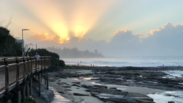 sunrise over a beach with a boardwalk